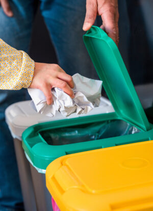 mixed race father and daughter recycling paper and throwing it into a garbage bin