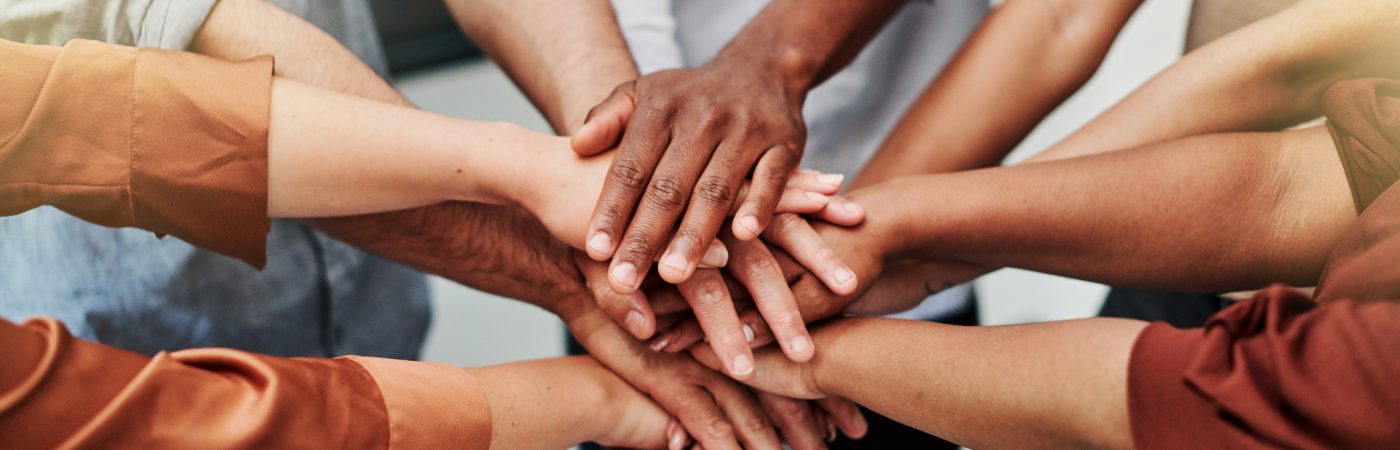 high angle shot of a group of unrecognisable businesspeople joining their hands together in a huddle