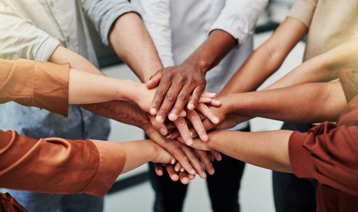 high angle shot of a group of unrecognisable businesspeople joining their hands together in a huddle