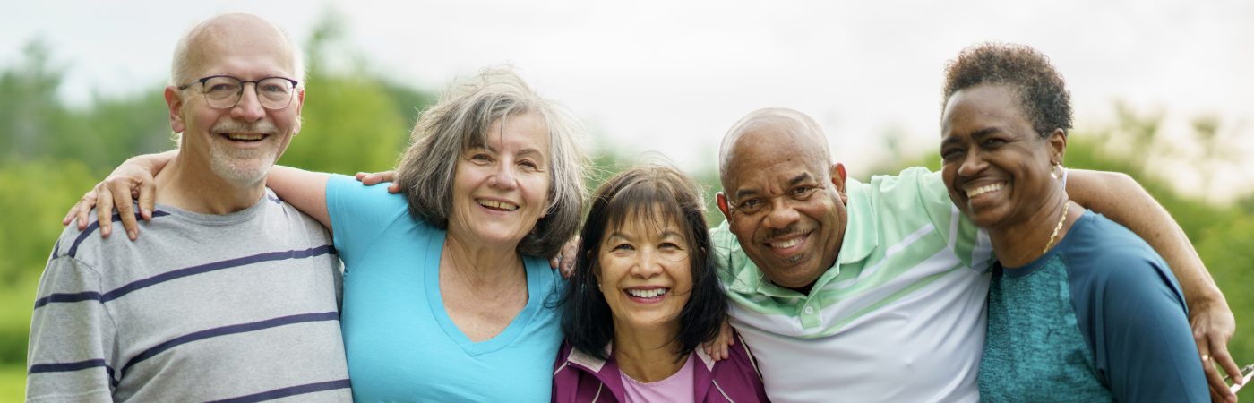 group of senior friends smiling outdoors during a sunny day
