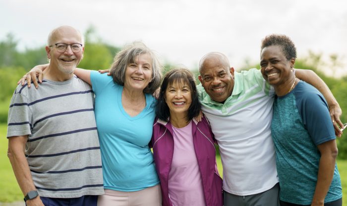 group of senior friends smiling outdoors during a sunny day