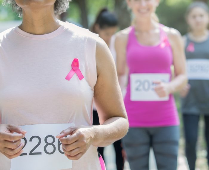 diverse unrecognizable women running in breast cancer charity race for cure