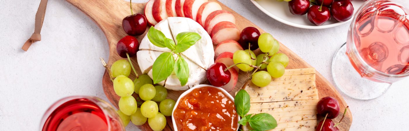 healthy mediterranean cheese and fruits board with rose wine on light background