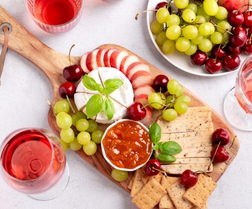 healthy mediterranean cheese and fruits board with rose wine on light background